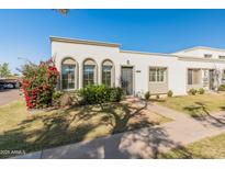 Charming townhome boasts a stucco exterior, arched windows, and a colorful flower bush at 8317 E Orange Blossom Ln, Scottsdale, AZ 85250