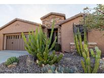 Charming home exterior with desert landscaping, showcasing native cacti and a stone facade entry at 27654 N 125Th Dr, Peoria, AZ 85383