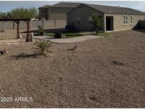 Large backyard with gravel landscaping, a pergola, and green grass, offering a versatile outdoor living space at 29908 W Monterey Dr, Buckeye, AZ 85396