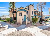 Charming stucco townhome with a quaint front entrance, complemented by desert landscaping and mature trees at 101 N 7Th St # 210, Phoenix, AZ 85034