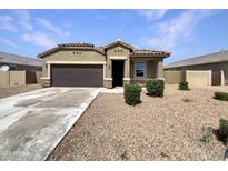 Charming single-story home featuring a desert landscape, covered entry, and a spacious concrete driveway at 35972 W Seville Dr, Maricopa, AZ 85138