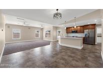 Spacious living room and kitchen area with tiled floors, ceiling fans, and stainless steel appliances at 3747 E Harmony Ave, Mesa, AZ 85206