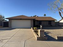 Charming brick home with a two-car garage, complemented by desert landscaping and a well-maintained front yard at 409 W Ross Ave, Phoenix, AZ 85027