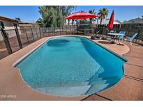 Backyard pool with privacy fence, surrounded by desert landscaping and a covered table with seating at 3661 W Oakland St, Chandler, AZ 85226