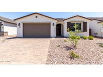 Beautiful single-story home with a brown garage door, tidy landscaping, and neutral-tone exterior paint at 5011 W Hardtack Trl, Laveen, AZ 85339