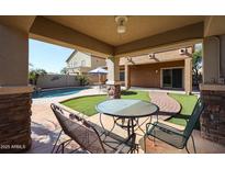 Enjoy outdoor dining under the covered patio with backyard views of the pool and artificial turf at 10037 W Chipman Rd, Tolleson, AZ 85353