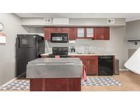 Functional kitchen features stainless steel island, black appliances, and warm cabinetry at 2315 W Union Hills Dr # 124, Phoenix, AZ 85027