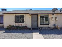 Exterior of a tan home featuring a security door, rock landscaping, and window bars at 3646 N 69Th Ave # 4, Phoenix, AZ 85033