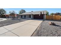 Charming single-story home with a gray rock yard, a long concrete driveway, and an attached two-car garage at 6029 W Pershing Ave, Glendale, AZ 85304