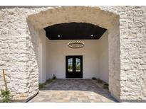 Grand entrance featuring stone archway, black double doors, and decorative chandelier at 7528 E Windrose Dr, Scottsdale, AZ 85260