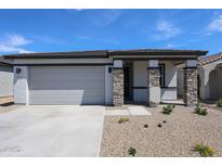 Charming single-story home with a two-car garage and a beautifully landscaped front yard under a clear sky at 18220 W Daley Ln, Surprise, AZ 85387