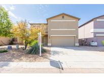 Two-story home with a tan stucco exterior, two-car garage, and low-maintenance desert landscaping at 1037 E Dust Devil Dr, San Tan Valley, AZ 85143