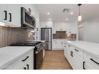 Modern kitchen with stainless steel appliances, gas range, white cabinetry, and a marble countertop island at 7507 E Beatrice St, Scottsdale, AZ 85257