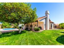 Spacious backyard featuring a healthy lawn, an orange tree, covered patio, and a sparkling blue pool at 930 E Citation Ln, Tempe, AZ 85284