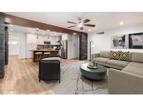 Open-concept living space with wood floors, stone accents, and a view of the modern kitchen at 7030 N 12Th St, Phoenix, AZ 85020