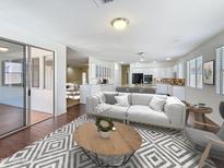 Spacious living room flowing into the kitchen, with a large sofa, stylish rug, and ample natural light at 14437 W Lexington Ave, Goodyear, AZ 85395