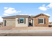 Charming single-story home featuring a stone facade, tan shutters, and a two-car garage at 26930 W Renee Dr, Buckeye, AZ 85396