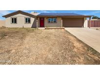 Tan single-story home featuring a red door, two-car garage, and solar panels on the roof at 3702 E Karen Dr, Phoenix, AZ 85032
