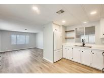 Bright kitchen featuring wood floors, white cabinets, and stainless appliances adjacent to the light-filled living room at 918 S Evangeline Ave, Mesa, AZ 85208