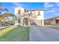Charming two-story home featuring a stucco facade, arched entryway, and well-maintained front yard at 40613 N Jerlyn Pl, San Tan Valley, AZ 85140