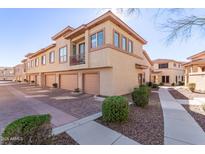 View of townhomes featuring private garages, patios, and well-maintained landscaping in a sunny neighborhood at 42424 N Gavilan Peak Pkwy # 63212, Anthem, AZ 85086