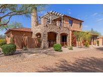 Stunning two-story home featuring stone accents, a pergola-covered balcony, and a terracotta tile roof at 7600 E Golden Eagle Cir, Gold Canyon, AZ 85118