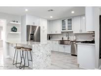 Bright kitchen with granite counters, stainless steel appliances, island with seating, and white cabinetry at 8408 E Lewis Ave, Scottsdale, AZ 85257
