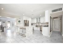 Bright kitchen with granite counters, stainless steel appliances, island with seating, and white cabinetry at 8408 E Lewis Ave, Scottsdale, AZ 85257