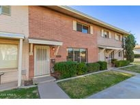 Charming brick townhome featuring a well-maintained lawn and cozy front entryway at 8443 E Montebello Ave, Scottsdale, AZ 85250