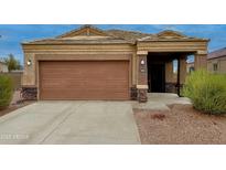 Charming single-story home featuring a brown garage door and desert landscaping at 4053 N 308Th Ln, Buckeye, AZ 85396