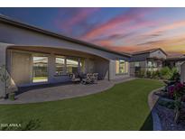 Well-manicured backyard features an extended patio, green synthetic grass and a lovely water feature at 459 E Bracciano Ave, Queen Creek, AZ 85140