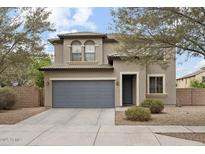 Charming two-story home featuring a gray garage door, desert landscaping and arched second story windows at 15758 W Cortez St, Surprise, AZ 85379