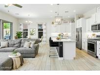 Spacious living room featuring a kitchen with stainless steel appliances, and a comfortable gray couch at 1816 N Bernard Cir, Mesa, AZ 85207