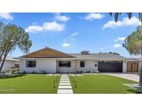 Inviting single-story home with manicured lawn, modern walkway, and neutral paint scheme under a partly cloudy blue sky at 8215 E Virginia Ave, Scottsdale, AZ 85257
