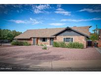 Charming single-story brick home featuring a well-maintained yard with mature landscaping at 1556 E Dover Cir, Mesa, AZ 85203