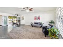 Bright living room featuring neutral carpet, two ceiling fans, and sliding glass doors leading to the outdoor area at 17885 N 99Th Dr, Sun City, AZ 85373