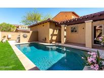 Refreshing backyard pool with cool turquoise water, surrounded by a stone patio and green artificial turf at 21152 W Sunrise Ln, Buckeye, AZ 85396
