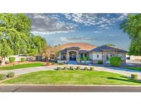 Beautiful single-story home with manicured lawn, circular driveway, and stone accents at 21470 E Orchard Ln, Queen Creek, AZ 85142