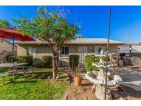 Charming home featuring a lush front yard with a fountain and outdoor seating area at 2306 E Burgess Ln, Phoenix, AZ 85042