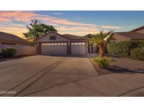 Charming single-story home showcasing a three-car garage and well-manicured landscaping and a beautiful sunset at 3841 E Redfield Ct, Gilbert, AZ 85234
