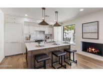 Modern kitchen features white cabinets, marble backsplash, and a wooden island with bar seating and statement pendant lighting at 7520 E Valley View Rd, Scottsdale, AZ 85250