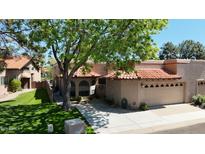 Charming home featuring a red tile roof, arched windows, and a well-manicured lawn, nestled under a mature shade tree at 11837 N 40Th Pl, Phoenix, AZ 85028