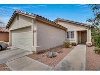 Inviting beige home featuring desert landscaping, a two-car garage, and a tile roof under a bright blue sky at 12048 W Dahlia Dr, El Mirage, AZ 85335