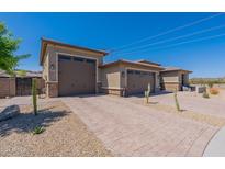 A three-car garage features neutral paint, a brick driveway, and desert landscaping under a clear blue sky at 18159 W Piro St, Goodyear, AZ 85338