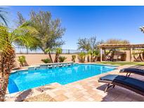Relaxing pool area with lounge chairs, rock water feature, and lush landscaping at 25862 N 108Th Ave, Peoria, AZ 85383