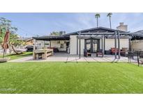 Spacious backyard with artificial turf, covered patio, pergola, and outdoor dining area, great for entertaining at 3246 E Palm Ln, Phoenix, AZ 85008