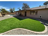 Spacious backyard with lush synthetic grass, rock landscaping, pool, and covered patio area at 2222 W Kristal Way, Phoenix, AZ 85027