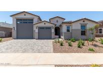 Charming, light-colored single-Gathering home featuring a large garage, front yard landscaping, and a paver driveway at 23724 N 165Th Dr, Surprise, AZ 85387