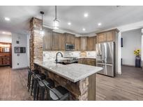 Charming kitchen with brick accents on the island, stainless steel appliances, and granite countertops at 8246 W Melinda Ln, Peoria, AZ 85382