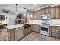 Updated kitchen with stainless steel appliances, granite countertops, and stone accents on the island at 8246 W Melinda Ln, Peoria, AZ 85382